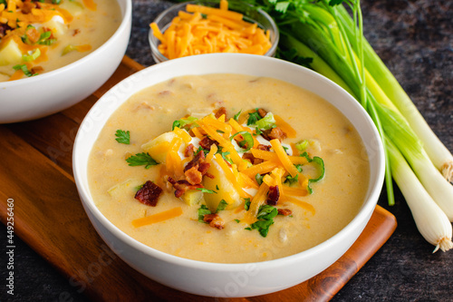 Bowls of Loaded Baked Potato Soup Topped with Sour Cream, Cheddar Cheese, Bacon, and Chives: Creamy potato soup garnished with sour cream, shredded cheese, bacon bits, and chives