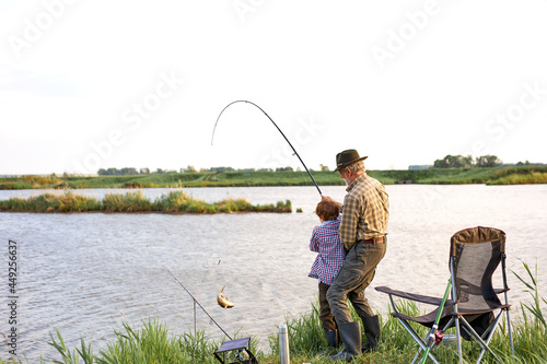 Man family fishing. Boy with grandfather catch the fish, fly fishing outdoor over river background. Old and young. Family time, hobby, happy childhood concept. copy space. rear view