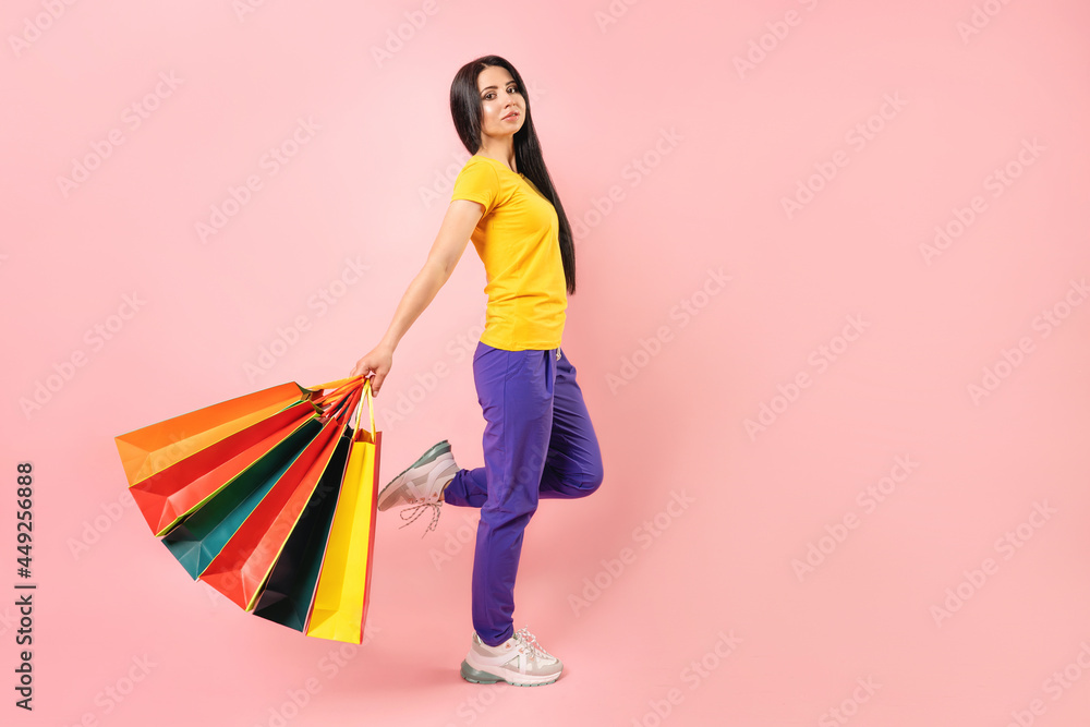 sales concept. Girl with colour paper bags on pink background sales concept. Girl with colour paper bags on pink background