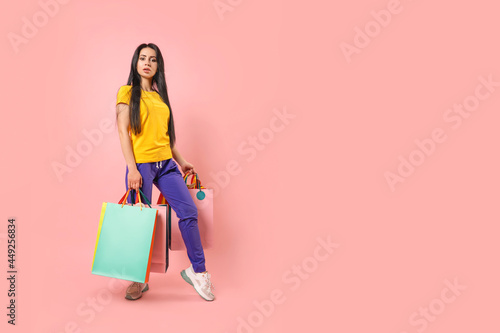 Full length photo of happy charming woman hold shopping bags customer isolated on pink color background