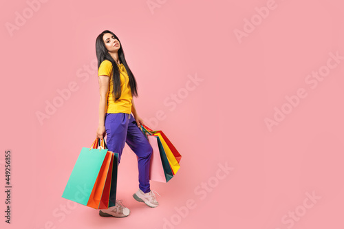 photo of happy woman with colorful shopping bags isolated on pink color background