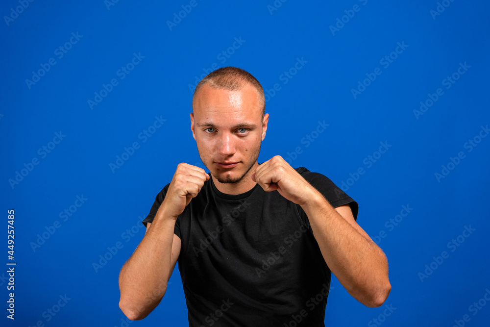 Naklejka premium Young handsome man isolated on blue background Ready to fight with fist defense gesture, angry and upset face, afraid of problem.