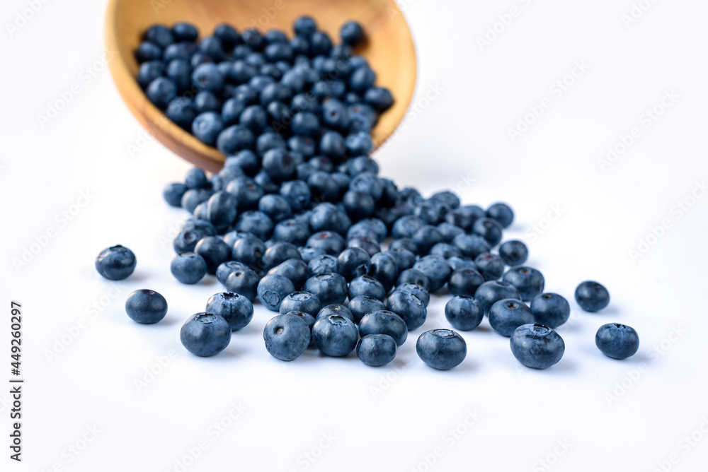 Fresh blueberries spilled from wooden bowl on blue wooden table. Healthy and dietary food concept. Blueberry is an antioxidant