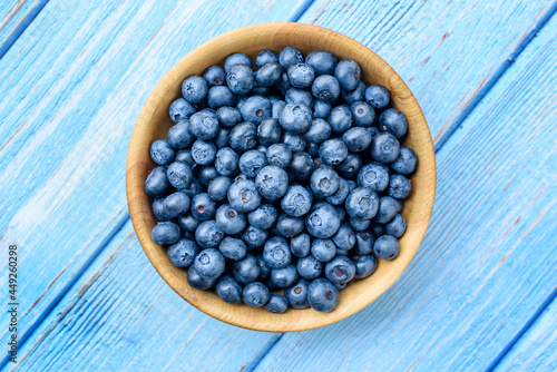 Fresh blueberries in a wooden bowl on an old blue wooden table. Healthy and dietary food concept. Blueberry is an antioxidant. Top View