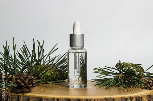 Obraz na płótnie A cosmetic transparent jar with a pipette is filled with oil and pine plant extract on a cut tree