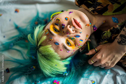 Closeup fashion portrait young pretty beautiful girl with green and blue hair. Beautiful fashion girl with luxury professional makeup and funny emoji stickers glued on the face. Young woman
