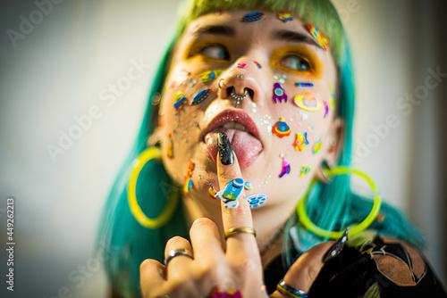 Closeup fashion portrait young pretty beautiful girl with green and blue hair. Beautiful fashion girl with luxury professional makeup and funny emoji stickers glued on the face. Young woman photo