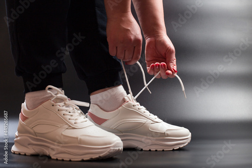 Tying shoelaces on sneakers. Stylish white sneakers for women.