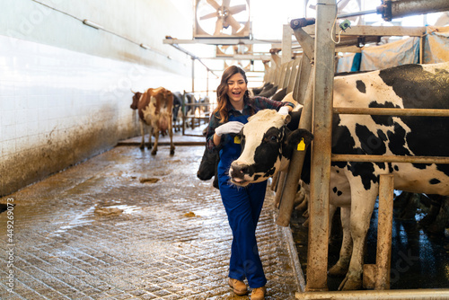 Obraz na plátně Smiling young woman stroking cow while standing in barn