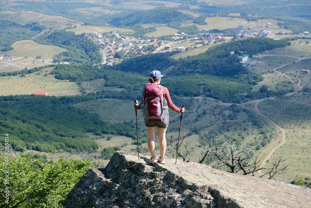 A girl with a hiking backpack stands on a cliff in the Crimean mountains. Demerdzhi mountain range.