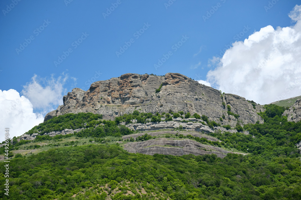 A massive rocky cliff called the Visor towering over a valley in the Crimea. Demerdzhi mountain range.