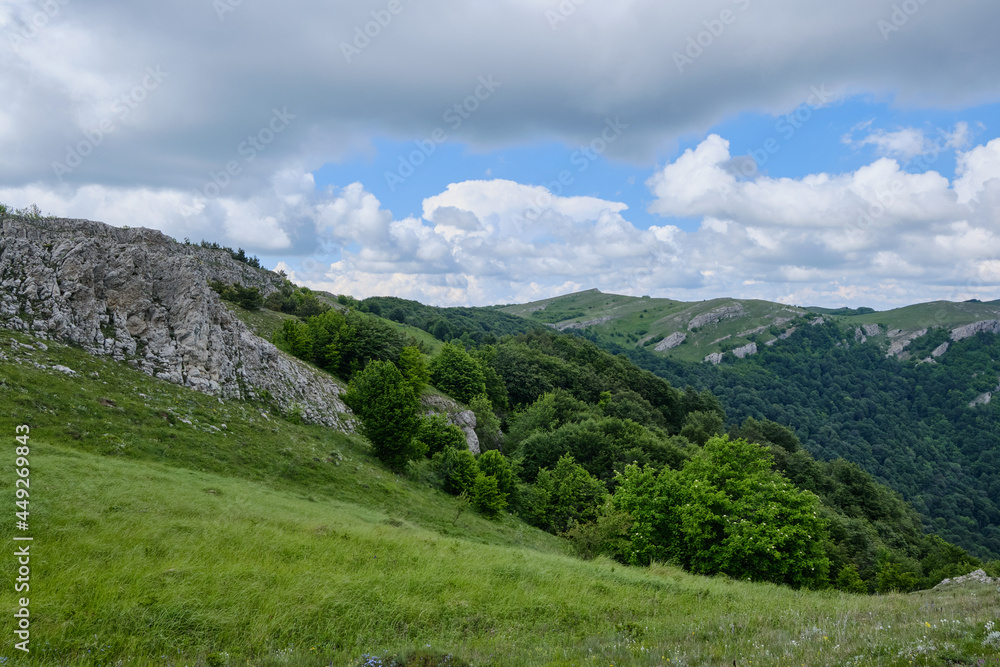 Bright green slopes of the Crimean mountains in cloudy summer weather. Demerdzhi mountain range, Crimea.