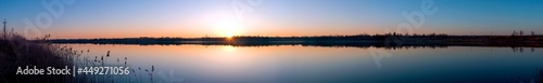 Photos Panorama of the evening lake with a swan and the sun, colorful shades in the sky