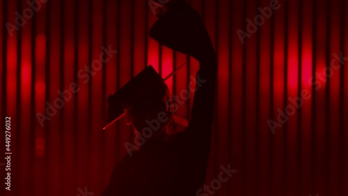 Beautiful hat dressed girl dancing latin dance . Professional female dancer dancing flamenco , rumba or salsa on red background with lines . Spanish dance movements . Shot ARRI ALEXA Cinema Camera . photo