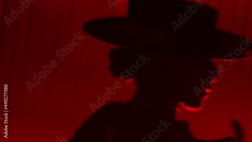 Beautiful hat dressed girl dancing latin dance . Professional female dancer dancing flamenco , rumba or salsa on red background with lines . Spanish dance movements . Shot ARRI ALEXA Cinema Camera .