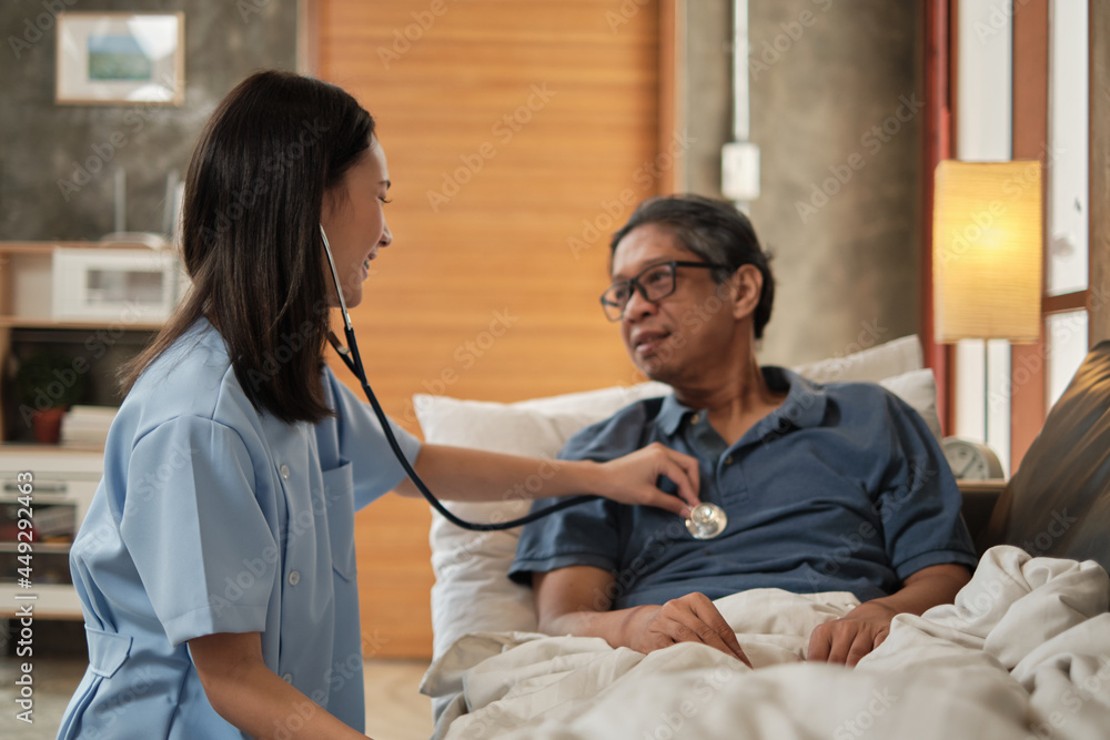 Female doctor checking the health of Asian elderly male patient at home as a medical service for visiting sick older people after retirement, medical support, residential caregiver from professional. Female doctor checking the health of Asian elderly male patient at home as a medical service for visiting sick older people after retirement, medical support, residential caregiver from professional.