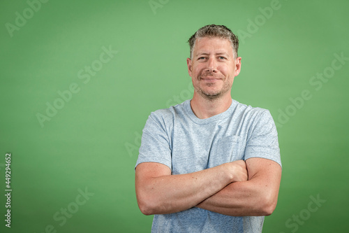 middle aged man with grey t-shirt and grey hair is posing in front of green background