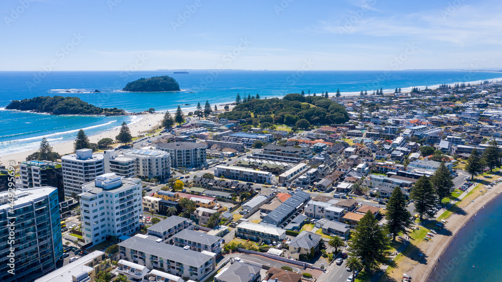 Fototapeta premium Aerial View from Houses close to the Beach, Green Trees, Mountain, Mount Maunganui, Boats in Tauranga, New Zealand - Bay of Plenty