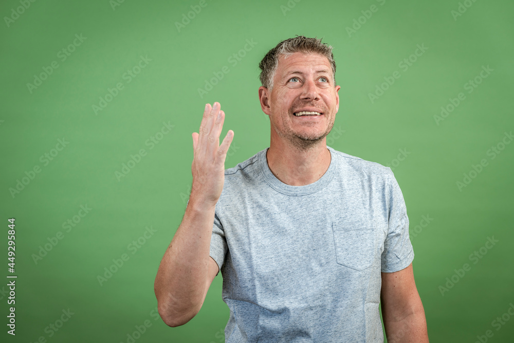 middle aged man with grey t-shirt and grey hair is posing in front of green background middle aged man with grey t-shirt and grey hair is posing in front of green background