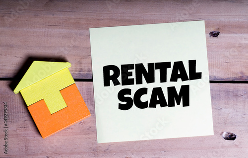 RENTAL SCAM text written on a paper with wooden table.