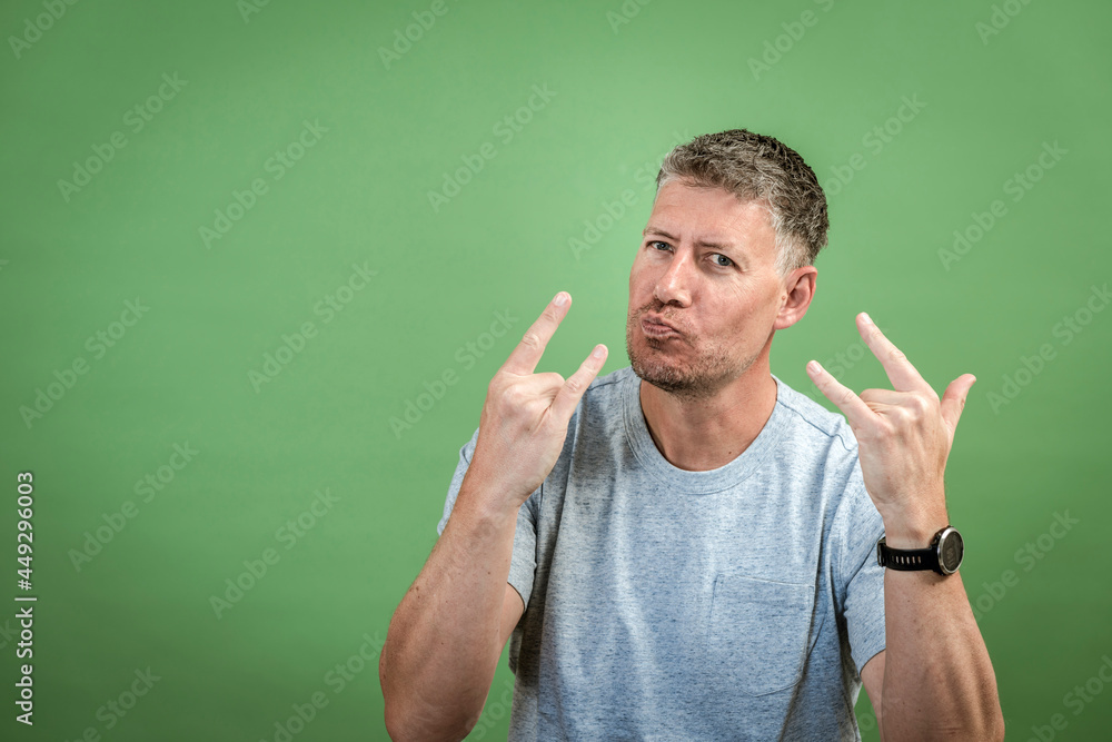 middle aged man with grey t-shirt and grey hair is posing in front of green background middle aged man with grey t-shirt and grey hair is posing in front of green background