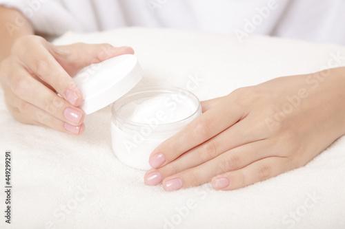 Woman's gentle hands with perfect manicure and a jar of cream