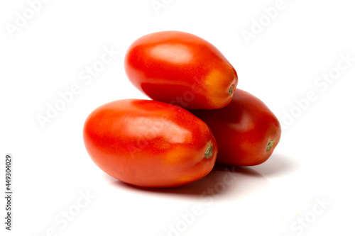 Three elongated red tomatoes lie on a white background.