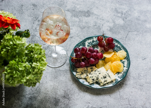 Fotografie Aperitif - cocktail and a plate with grapes, cheese and chips on a gray backgrou