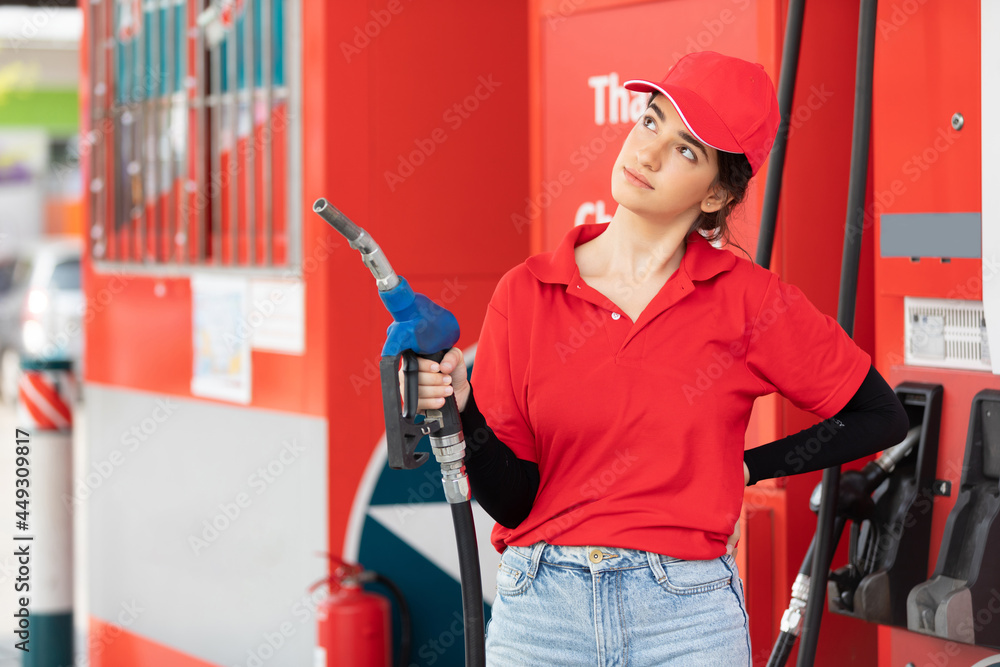 portrait young woman worker holding petrol hose and thinking something at the gas station portrait young woman worker holding petrol hose and thinking something at the gas station