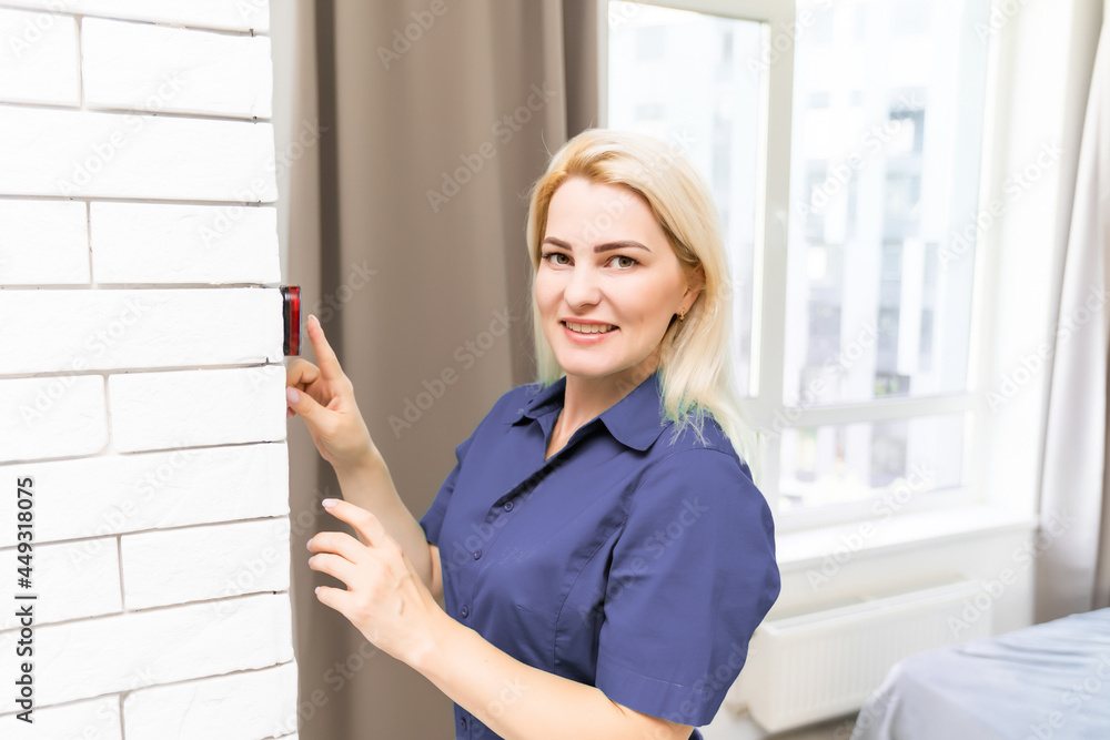 A woman is pressing the up button of a wall attached house thermostat with digital display showing the temperature. A concept image for electricity bill, heating, cooling, eco friendly, saving etc A woman is pressing the up button of a wall attached house thermostat with digital display showing the temperature. A concept image for electricity bill, heating, cooling, eco friendly, saving etc