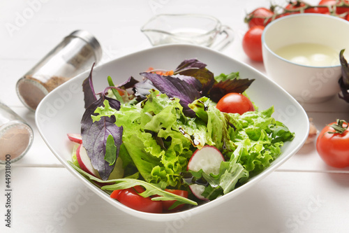 Bowl with tasty fresh salad on light wooden background, closeup