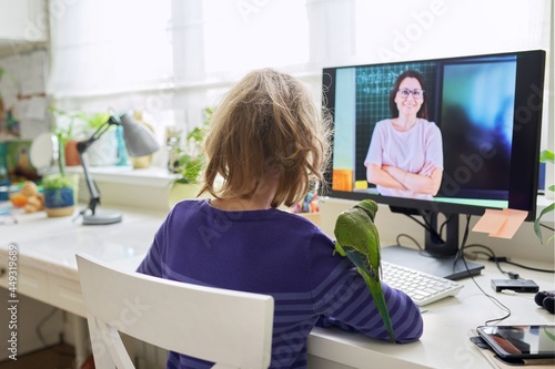 Child preteen girl studying at home using video lesson on computer photo