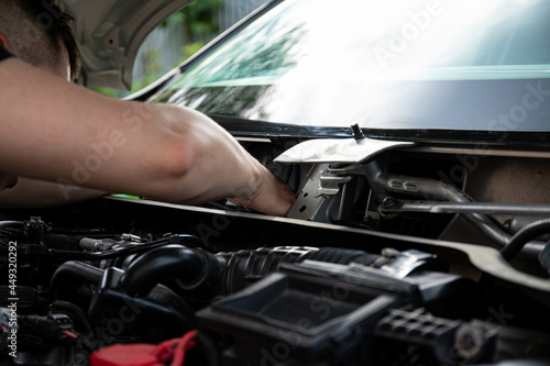 a man repairs a car. a man in blue special clothes to repair the car. engine parts machine repair maintenance breakage problem hands people man master