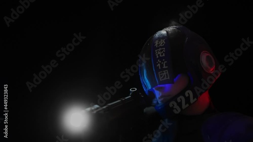 Cyberpunk future concept. Police officer, bionic cyborg or robot aims weapon gun with lantern in dark. Halfman goes to camera and leaves frame. Science fiction scene, fantasy, sci. Red blue light photo