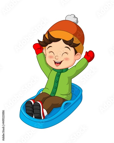 Cute little boy sledding down a hill