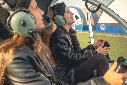 Smiling preteen girls in headsets looking up at sky in helicopter cockpit photo