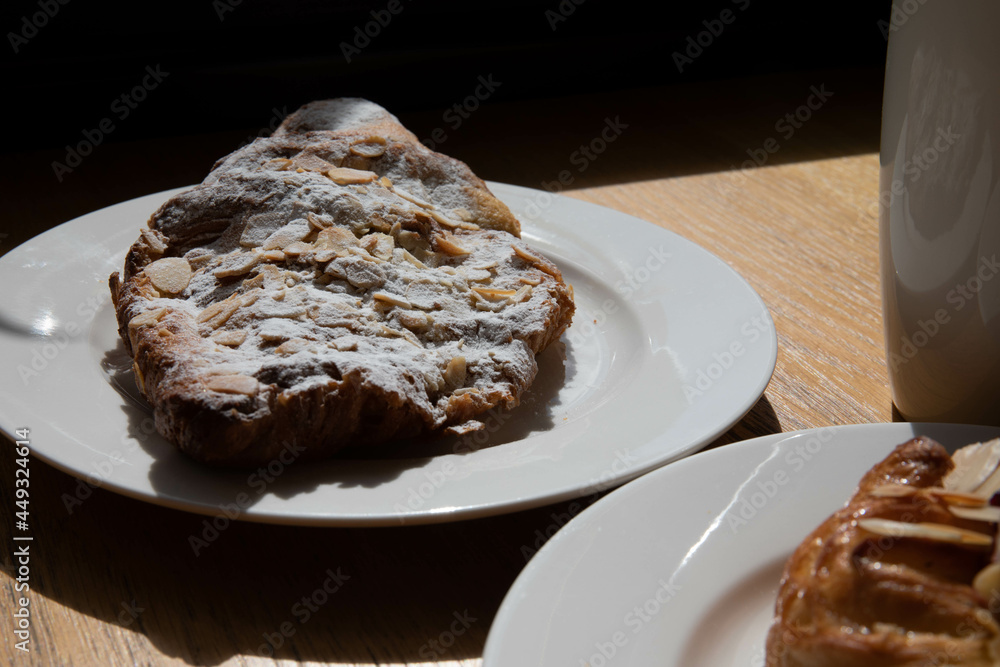 an almond croissant and a bun with strawberry slices lie on a white plate next to a white cup of coffee cappuccino and latte food fresh pastries bakery handmade kitchen cafe breakfast health an almond croissant and a bun with strawberry slices lie on a white plate next to a white cup of coffee cappuccino and latte food fresh pastries bakery handmade kitchen cafe breakfast health