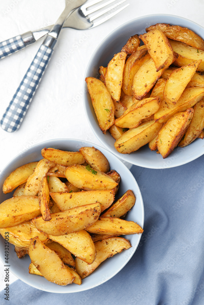 Bowls with tasty baked potato on light background Bowls with tasty baked potato on light background