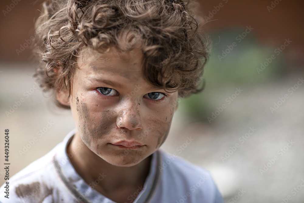 A homeless orphan boy looks with eyes full of tears