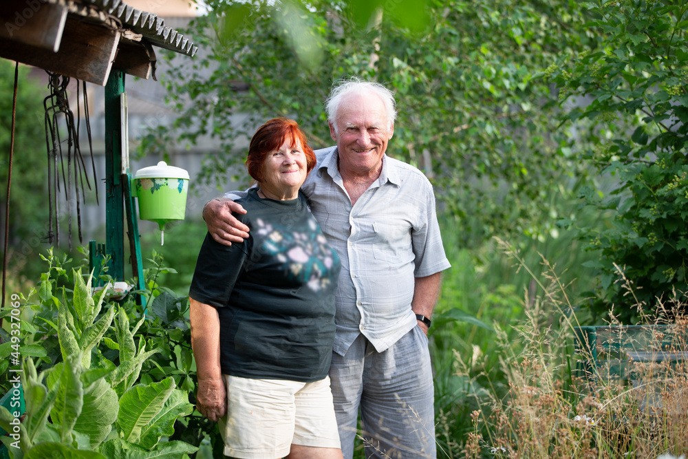 A beautiful very elderly couple hugs and looks at the camera at the dacha. A beautiful very elderly couple hugs and looks at the camera at the dacha.
