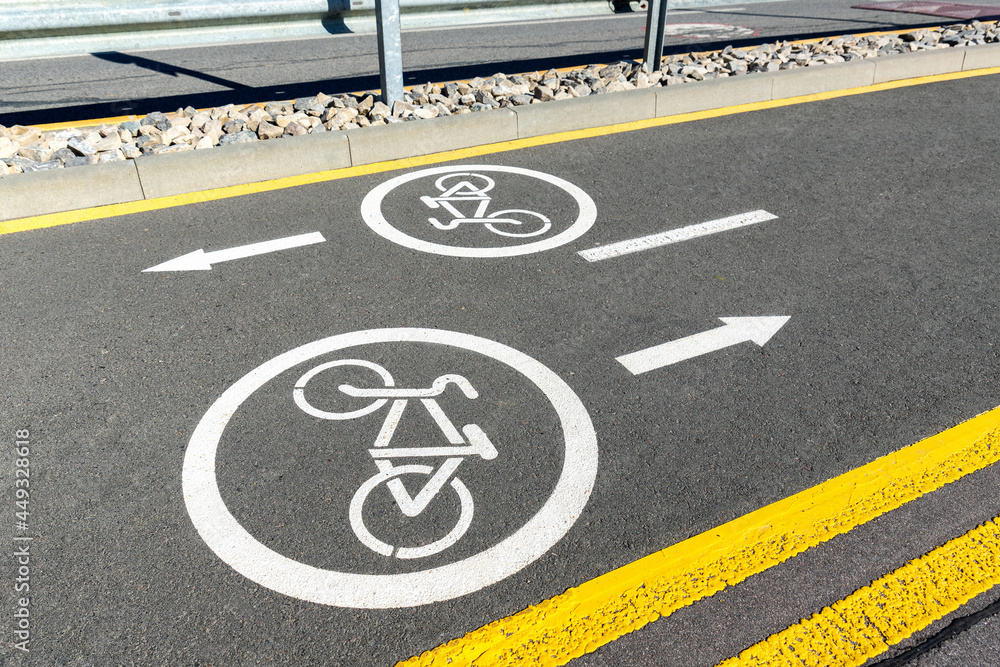 Fototapeta premium City street asphalt road with separated two way direction bicycle lane route sign mark with white paint. Modern eco urban commute transportation infastrucutre organization. Healthy lifestyle concept