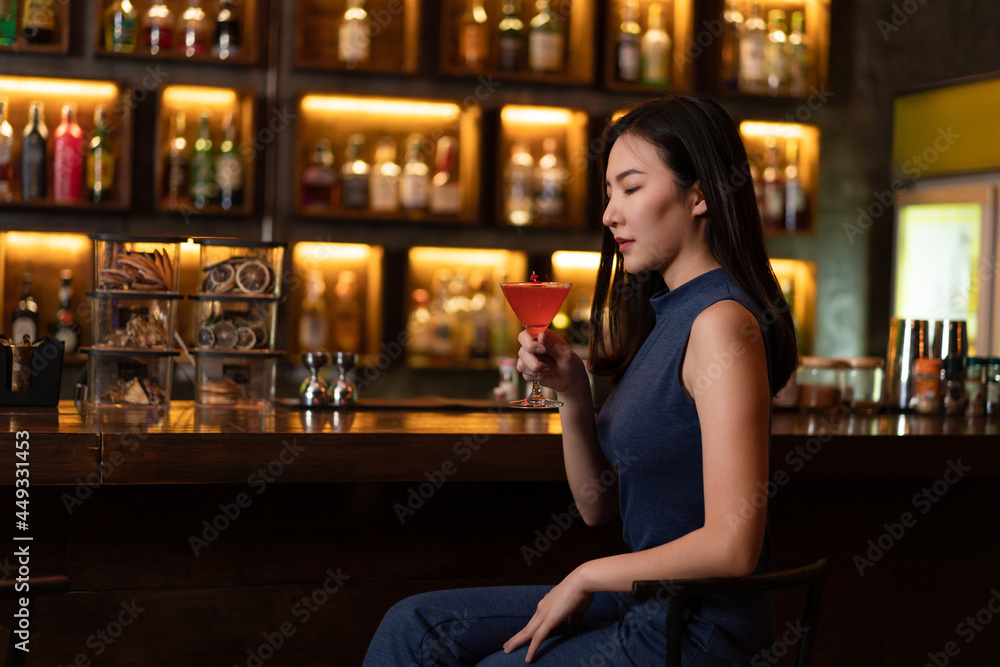 Nightlife concept a pretty girl with long hair wearing blue dress holding a pink drink appreciating the musics alone in the bar Nightlife concept a pretty girl with long hair wearing blue dress holding a pink drink appreciating the musics alone in the bar