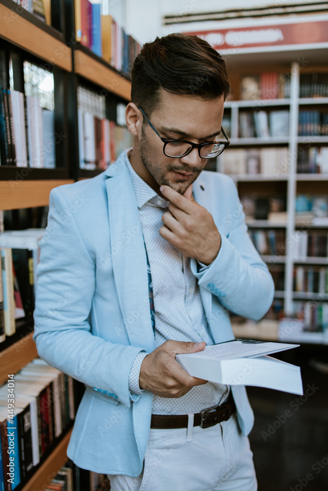 Middle age man choosing and reading books in modern bookstore.