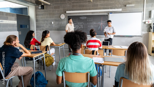 Teen asian boy high school student giving a presentation in class to his multiracial classmates and teacher. Horizontal banner image. photo