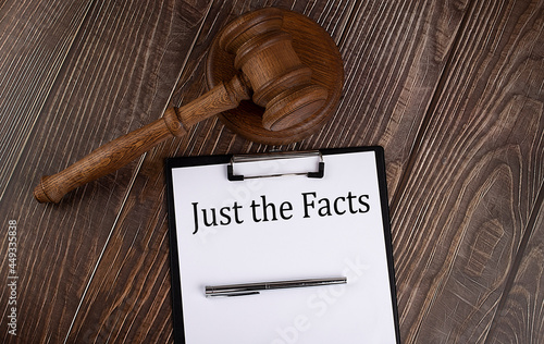 JUST THE FACTS text on paper with gavel on wooden background photo