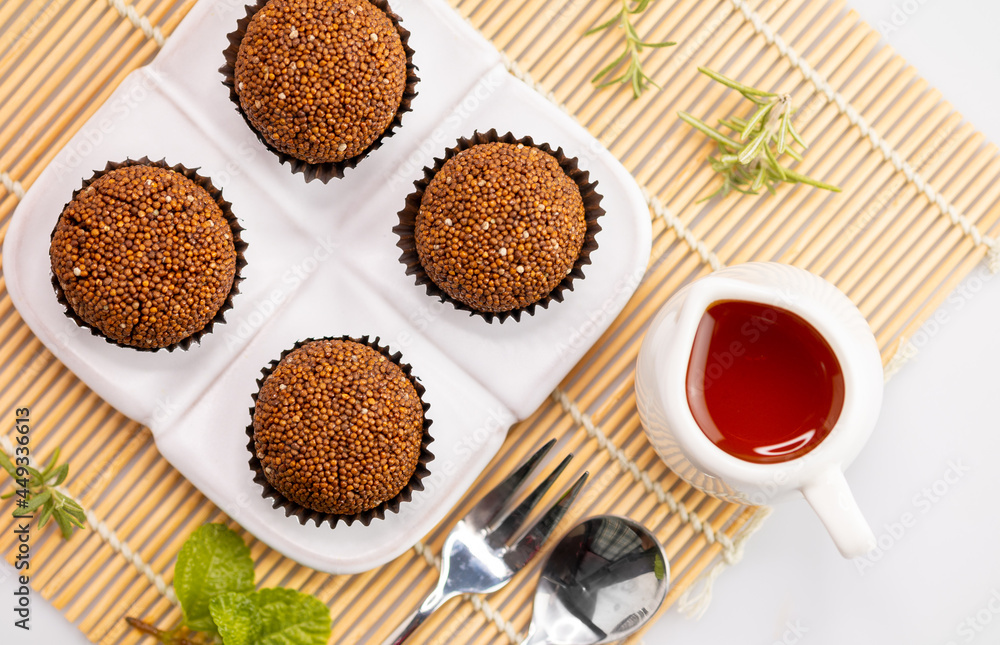 Perilla seed mixed with Jaggery palm sugar and mold into a ball place on a white plate decorated with mint leaves on a bamboo mat with spoons and forks. Perilla seed mixed with Jaggery palm sugar and mold into a ball place on a white plate decorated with mint leaves on a bamboo mat with spoons and forks.