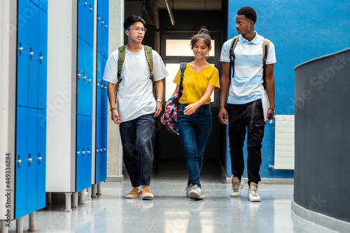 фотографія Group of multiracial teen high school students changing classes walking in school corridor
