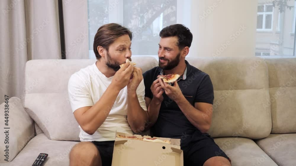 Male same sex couples meeting at home and eating takeaway pizza together. Leisure of family gays, homosexuals. Lgbt couple. Weekend, vacation, end of working week. Harmful lifestyle, nutrition. Rest. Male same sex couples meeting at home and eating takeaway pizza together. Leisure of family gays, homosexuals. Lgbt couple. Weekend, vacation, end of working week. Harmful lifestyle, nutrition. Rest.