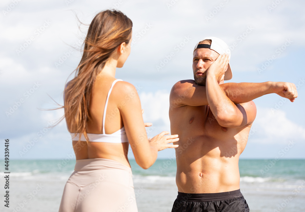 Fototapeta premium young man stretching and exercising outdoors from trainer suggesting on the beach