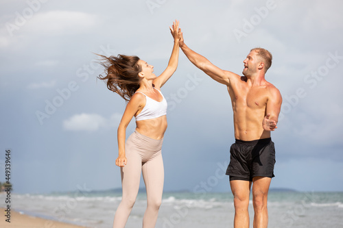 young couple jumping and giving high five pose on the beach © offsuperphoto